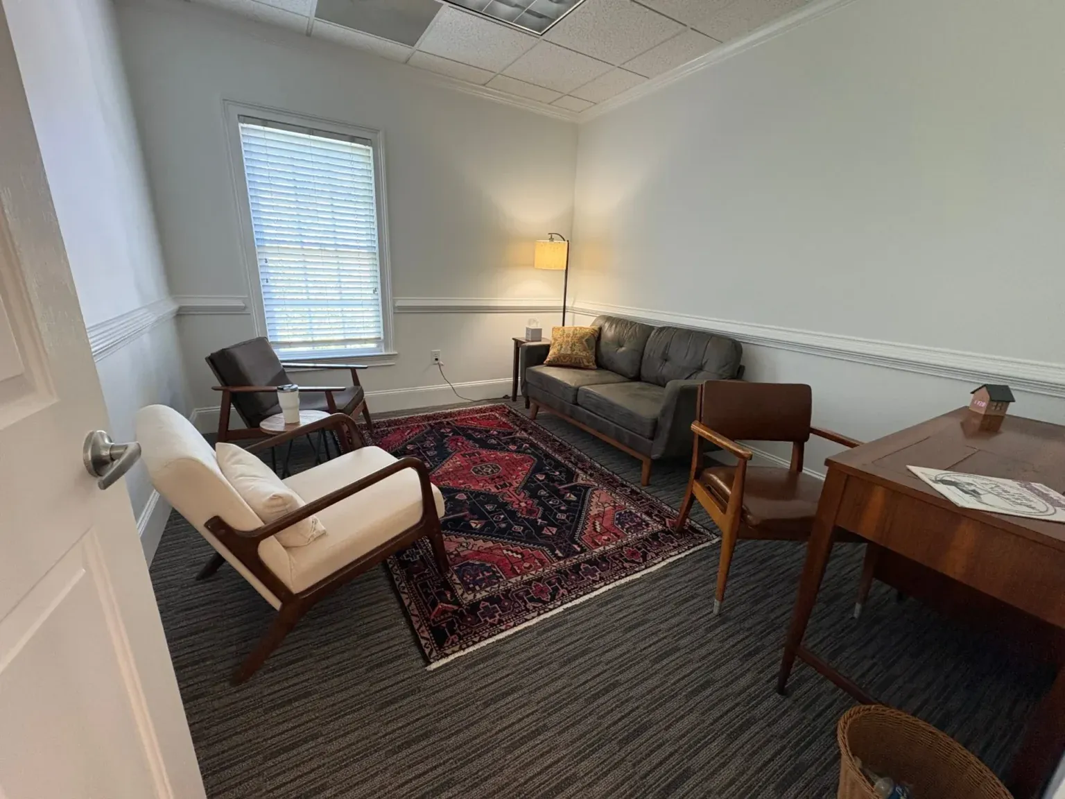 Therapy office at The Community with a sofa, armchairs and a red rug.